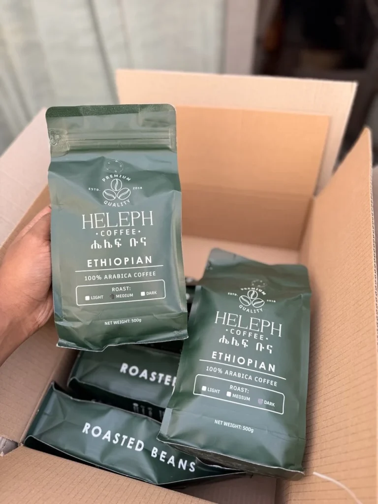 Hand holding Heleph Ethiopian 100% Arabica coffee bags in a shipping box