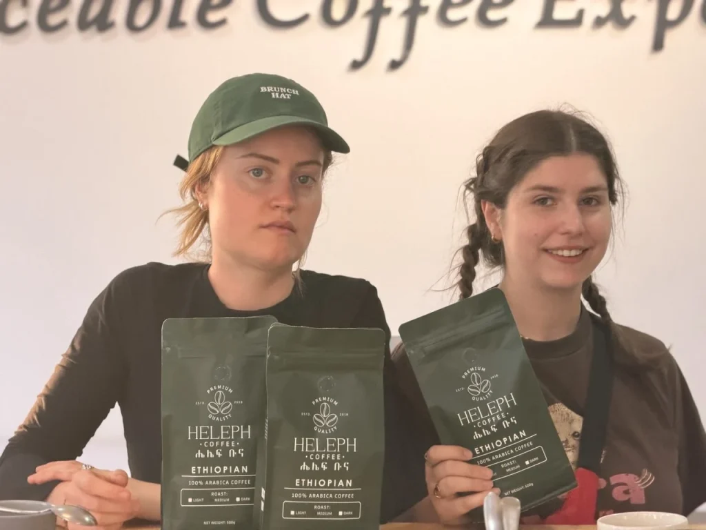 Two visitors holding Heleph Ethiopian coffee bags