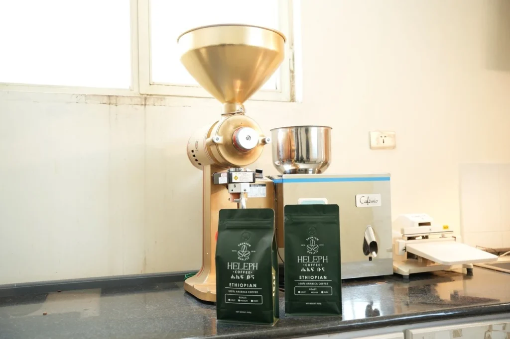 Heleph coffee bags beside a commercial coffee grinder